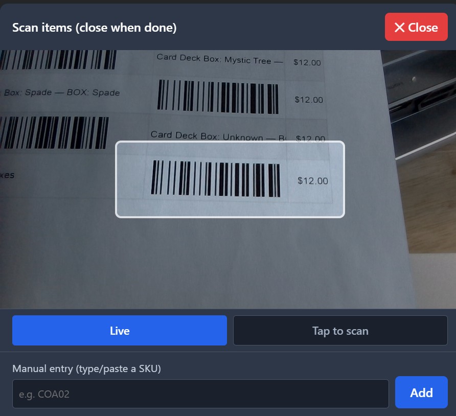 The camera scan view reading a Code 128 barcode label on a printed sheet, with a manual SKU entry box below.